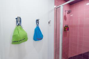 twee groene en blauwe zakken hangend aan een muur in een badkamer bij The Gallatin in Nashville