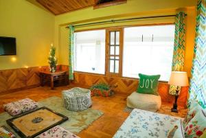 a living room with a couch and a table at Tropical Wood Villa in Manāli