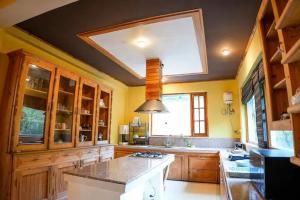 a large kitchen with yellow walls and a skylight at Tropical Wood Villa in Manāli
