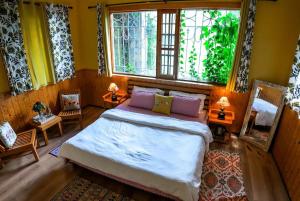 a bedroom with a large bed and two windows at Tropical Wood Villa in Manāli