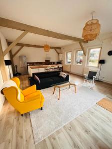 a living room with a black couch and yellow chairs at Jacqueline in Étretat