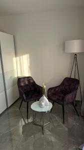 Zimmer mit 2 Stühlen, einem Tisch und einer Lampe in der Unterkunft Luxus-Flat Wohnung-Hanau/Frankfurt in Hanau am Main