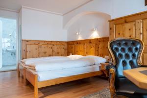 a bedroom with a bed and a chair at Hotel Bären in St. Moritz