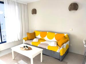 a living room with a yellow couch and a table at Sea view - Big Terrace - Sunset in Taurito