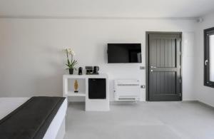 a white room with a bed and a tv at Arany Terra in Imerovigli