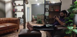 a man sitting in a chair with his feet on a computer at The Teal Cottage in Murree