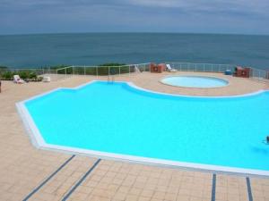 a large blue swimming pool next to the ocean at Studio cosy vue et front de mer in Sète