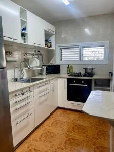 a kitchen with white cabinets and a black appliance at Bat Yam Garden in Bat Yam