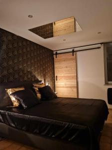 1 dormitorio con cama negra y puerta de madera en Les bulles d'or, en Flémalle-Grande