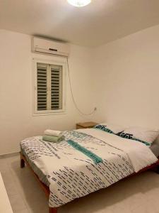 a white bedroom with a bed with a window at Bat Yam Garden in Bat Yam