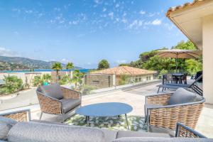 a patio with chairs and tables and a view of the ocean at Akwabay - Les Villas du Cap in Le Lavandou