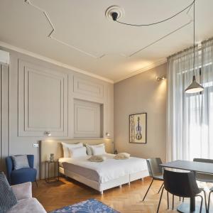 um quarto com uma cama, uma mesa e cadeiras em URBANAUTS BELETAGES Sonata em Trieste