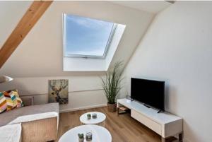 ein Wohnzimmer mit einem Sofa und einem Flachbild-TV in der Unterkunft Charmante Dachgeschosswohnung mit Balkon in Bruckmühl