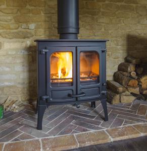 a stove with a fire inside of it at Pea Cottage in Stamford