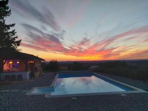 a swimming pool with a sunset in the background at Quatre Vents in Lagarrigue