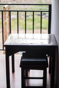 a table and a stool in front of a window at BK Hotel in Mae Sariang