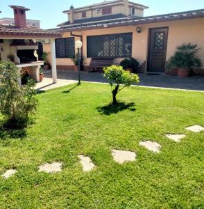 una casa con césped con un árbol en el patio en ZÍ MARIO Suite degli Ospiti - Roma Ostia Antica, en Ostia Antica