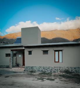 uma casa branca com montanhas ao fundo em Alojamiento La Bonita de Maimará em Maimará