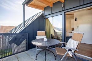 a patio with a table and chairs on a balcony at Charmante Dachgeschosswohnung mit Balkon in Bruckmühl