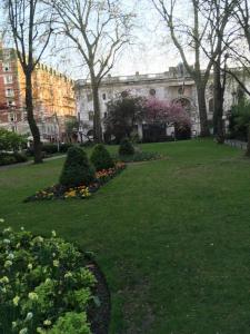 a park with flowers and trees and a building at Walk to Notting Hill /Paddington 1 B/R with patio in London
