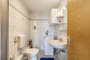 a white bathroom with a toilet and a sink at Ferienwohnung Am Wald in Herscheid