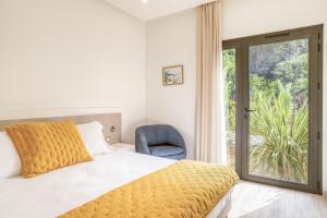 a bedroom with a bed and a chair and a window at Akwabay - Les Villas du Cap in Le Lavandou