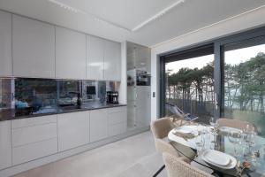 a kitchen with white cabinets and a table with chairs at HEVENIA POGORZELICA - Apartament 4 z bezpośrednim widokiem na morze in Pogorzelica +22 photos