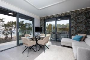 a living room with a couch and a table and chairs at HEVENIA POGORZELICA - Apartament 4 z bezpośrednim widokiem na morze in Pogorzelica