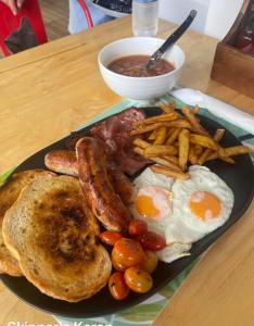 talerz jedzenia śniadaniowego z jajkami, kiełbasą i frytkami w obiekcie Skipper's Karon w mieście Karon Beach