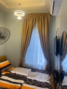 a bedroom with a bed and a window with curtains at BLUE AO HOTEL AND SUITES in Lagos