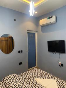 Zimmer mit einem TV und einer Tür mit einem Spiegel in der Unterkunft BLUE AO HOTEL AND SUITES in Lagos
