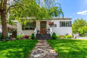 a white house with a tree and green grass at Copper Voyage, Fenced Backyard in Coeur d'Alene