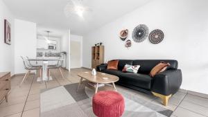 - un salon avec un canapé noir et une table dans l'établissement Homey Coloc Dolce - Proche gare et tram, Balcon, Wifi, à Ambilly