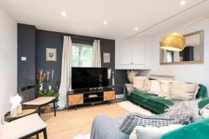 un soggiorno con divano verde e TV di Well Located Stylish 5 Bed House a Kent