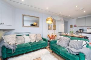 un soggiorno con 2 divani verdi e una cucina di Well Located Stylish 5 Bed House a Kent