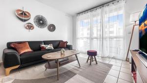 un soggiorno con divano nero e tavolo di Homey Coloc Dolce - Proche gare et tram, Balcon, Wifi ad Ambilly