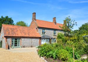 an old stone house with a red roof at Mulberry House in Bodham