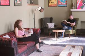 two people sitting on a couch in a living room at PH Hostel Liverpool in Liverpool