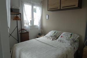 a bedroom with a bed with a pillow and a window at Les jardins de Bandol, piscine et mer in Bandol