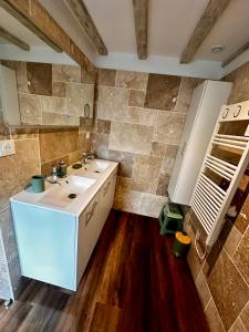 a bathroom with a white sink and a tile wall at Maison coeur de ville Montchanin in Montchanin