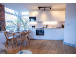 a kitchen with white cabinets and a table with chairs at Churchside Apartments in Eccles near Trafford and Salford in Manchester