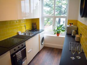 a kitchen with yellow tiles and a sink and a window at *Leamington Apartments* - Avenue Road - 1 bedroom apartment in Leamington Spa +4 photos