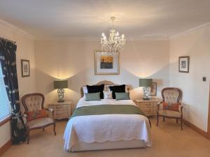 a bedroom with a bed with two chairs and a chandelier at Arden Country House in Linlithgow
