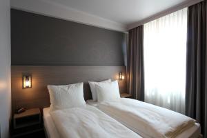 Schlafzimmer mit einem Bett mit weißer Bettwäsche und einem Fenster in der Unterkunft Grand Hotel Monopole in Valkenburg