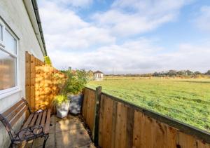 a porch with a bench and a fence and a field at Little Oldbury in Hevingham