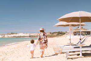 een vrouw en een kind die op het strand lopen bij Luna Minoica Suites and Apartments in Montallegro