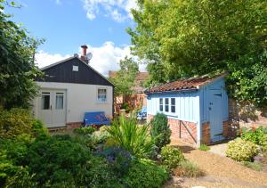 a small cottage with a blue shed in a garden at Moon Beam in Aylsham