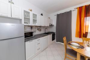 a kitchen with white cabinets and a wooden table with a tableablish at Kuća za odmor Pixie in Vrsi