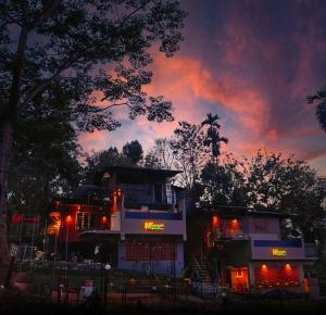 a building with red lights in front of a sunset at MANNATH POOL VILLA in Kozhikode