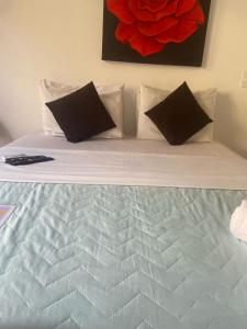 uma cama branca com almofadas pretas e uma pintura vermelha em Hotel Pousada Iracemar - Guarujá no Guarujá